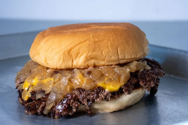 A cheeseburger with crisp beef edges, melted cheese and caramelized onions
