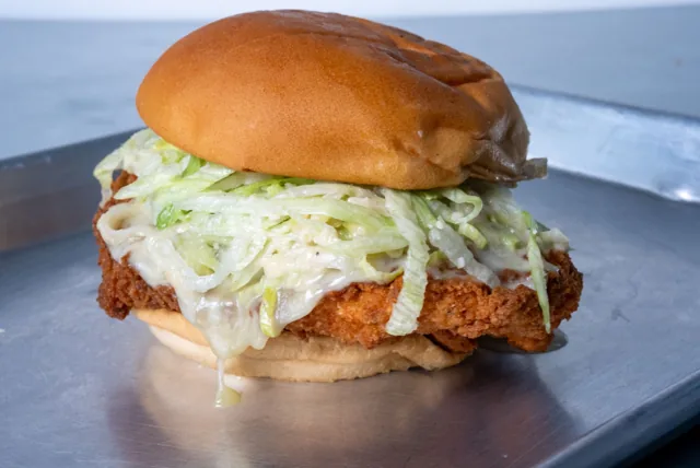 A crispy chicken sandwich topped with shredded lettuce and sauce